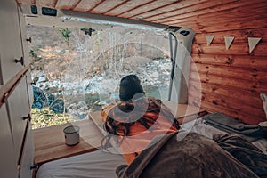 Vanlife - Young woman lying in camping van and looking at beautiful nature