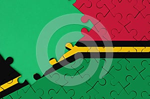 Vanuatu flag is depicted on a completed jigsaw puzzle with free green copy space on the left side