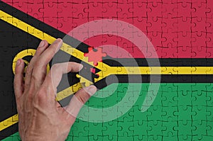 Vanuatu flag is depicted on a puzzle, which the man`s hand completes to fold