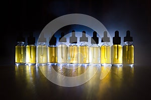 Vape concept. Smoke clouds and vape liquid bottles on dark background. Light effects.