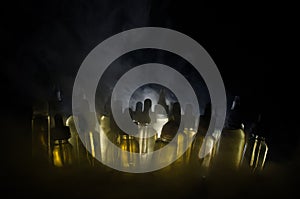 Vape concept. Smoke clouds and vape liquid bottles on dark background. Light effects.