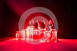 Vape concept. Smoke clouds and vape liquid bottles on dark background. Light effects.