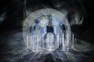 Vape concept. Smoke clouds and vape liquid bottles on dark background. Light effects. Useful as background or vape advertisement.