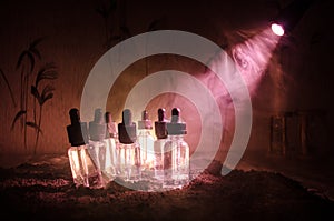 Vape concept. Smoke clouds and vape liquid bottles on dark background. Light effects. Useful as background or vape advertisement.