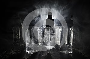 Vape concept. Smoke clouds and vape liquid bottles on dark background. Light effects. Useful as background or vape advertisement.