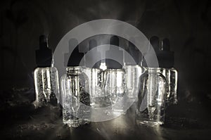 Vape concept. Smoke clouds and vape liquid bottles on dark background. Light effects. Useful as background or vape advertisement.