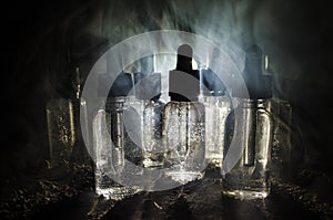 Vape concept. Smoke clouds and vape liquid bottles on dark background. Light effects. Useful as background or vape advertisement.