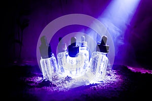 Vape concept. Smoke clouds and vape liquid bottles on dark background. Light effects. Useful as background or vape advertisement.