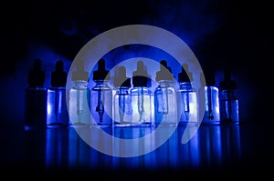 Vape concept. Smoke clouds and vape liquid bottles on dark background. Light effects. Useful as background or vape advertisement o