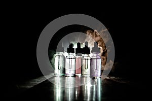 Vape concept. Smoke clouds and vape liquid bottles on dark background. Light effects. Useful as background or vape advertisement o