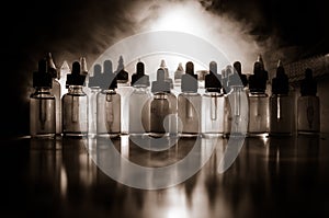 Vape concept. Smoke clouds and vape liquid bottles on dark background. Light effects. Useful as background or vape advertisement o