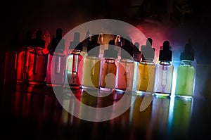 Vape concept. Smoke clouds and vape liquid bottles on dark background. Light effects. Useful as background or vape advertisement o