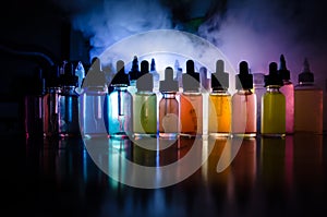 Vape concept. Smoke clouds and vape liquid bottles on dark background. Light effects. Useful as background or vape advertisement o