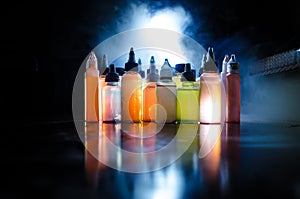 Vape concept. Smoke clouds and vape liquid bottles on dark background. Light effects. Useful as background or vape advertisement o