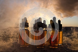 Vape concept. Smoke clouds and vape liquid bottles at sunset time. Blured background. Light effects. Useful as background or vape