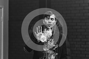 Vape man. Young handsome white guy let rings out of steam from electronic cigarette. Black and white photo.