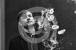 Vape man. Young handsome white guy let rings out of steam from electronic cigarette. Black and white photo.