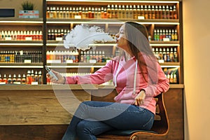 Vape woman. Young cute girl in pink hoodie smoking an electronic cigarette.