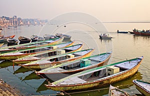 Varanasi, India: Bunch of old wooden colorful boats docked in the bay of Ganges river bank during sunset