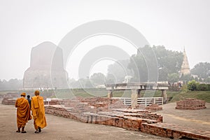 VARANASI, INDIA - DECEMBER 2, 2016: Buddhist monks and tourists come to visit and pray in the misty morning at Dhamekh Stupa.