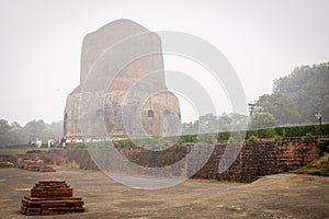 VARANASI, INDIA - DECEMBER 2, 2016: Buddhist monks and tourists come to visit and pray in the misty morning at Dhamekh Stupa.