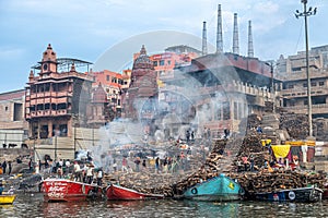 old wooden boats at the pier on the border of river Ganges in morning light with people on pier in Varanasi