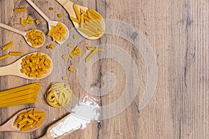 Vari mix di pasta su fondo rustico in legno, sacco e cucchiai di legno. Concetto di dieta e cibo