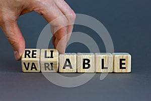 Variable or reliable symbol. Businessman turns wooden cubes and changes the word variable to reliable. Beautiful grey background,