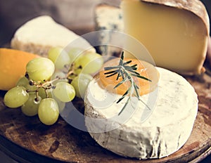 Variation of cheese and green grapes on a wooden platter food ph