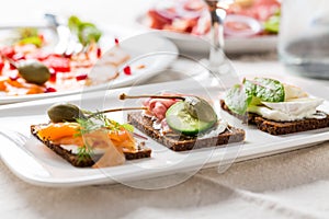 Variation of healthy open sandwiches on Pumpernickel bread with vegetables, salmon, Prosciutto and appetizers