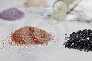 Variations of salts, red, lava, purple, pink; Himalayan and sea salts on a marble counter top background