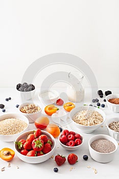 Variaty of raw cereals, fruits and nuts for breakfast. Oatmeal flakes and steel cut, barley, walnut, chia, apricot, strawberry.