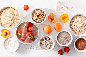 Variaty of raw cereals, fruits and nuts for breakfast. Oatmeal flakes and steel cut, barley, walnut, chia, apricot, strawberry.