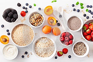 Variaty of raw cereals, fruits and nuts for breakfast. Oatmeal flakes and steel cut, barley, walnut, chia, apricot, strawberry.