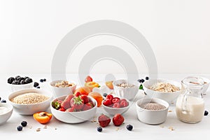 Variaty of raw cereals, fruits and nuts for breakfast. Oatmeal flakes and steel cut, barley, walnut, chia, apricot, strawberry.