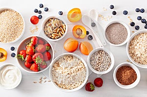 Variaty of raw cereals, fruits and nuts for breakfast. Oatmeal flakes and steel cut, barley, walnut, chia, apricot, strawberry.