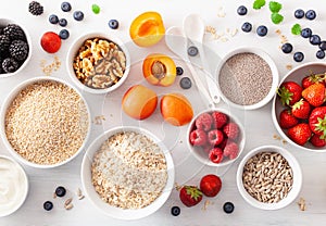 Variaty of raw cereals, fruits and nuts for breakfast. Oatmeal flakes and steel cut, barley, walnut, chia, apricot, strawberry.