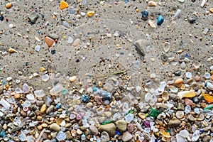 Varied microplastics and debris scattered on beach sand photo