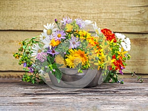 A variegated bouquet of summer wildflowers in a metal cup close-up