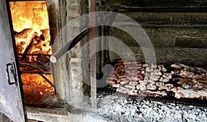 A Varierty of Meats cooking on a charcoal heated bbq.