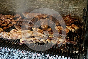 A Varierty of Meats cooking on a charcoal heated bbq.