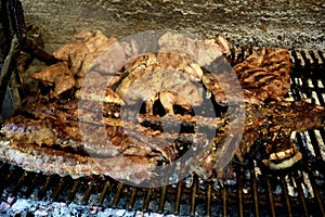 A Varierty of Meats cooking on a charcoal heated bbq.