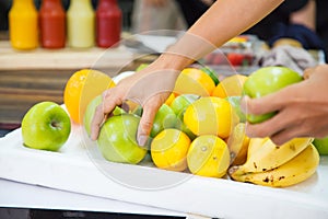 Varieties of fresh fruits bananas, oranges, limes, apples on white tray in market stall, used as ingredients for fruit smoothies