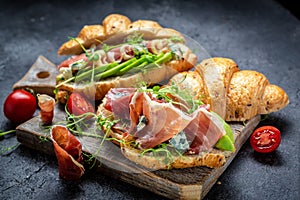 Variety of aperitifs Croissant sandwiches with jamon ham serrano paleta iberica, blue cheese, avocado, microgin on blue background