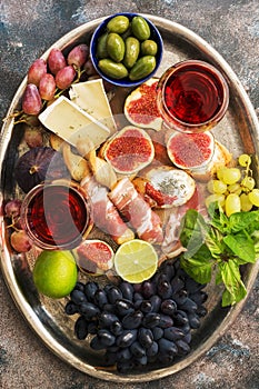 A variety of appetizer, prosciutto,grapes, wine, cheese with mold, figs, olives on a metal tray. Mediterranean snack.Top view,flat