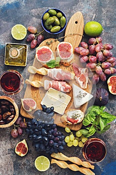 A variety of appetizer, prosciutto,grapes, wine, cheese with mold, figs, olives on a rustic background. Mediterranean snack.Top vi