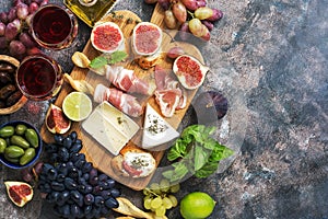 A variety of appetizer, prosciutto,grapes, wine, cheese with mold, figs, olives on a rustic background. Mediterranean snack.Top vi