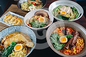 A variety of Asian dishes are displayed on a table, including bowls of ramen