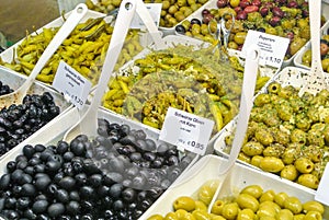 Variety assortment diverse of fresh healthy tasty green and black olives in white plastic bowls for sale on open street city mark