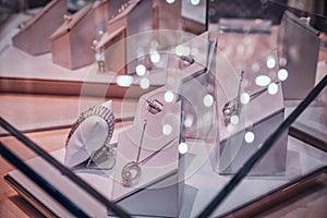 Variety of beautiful gold ornamentations on the white display under the glass in jewellery shop